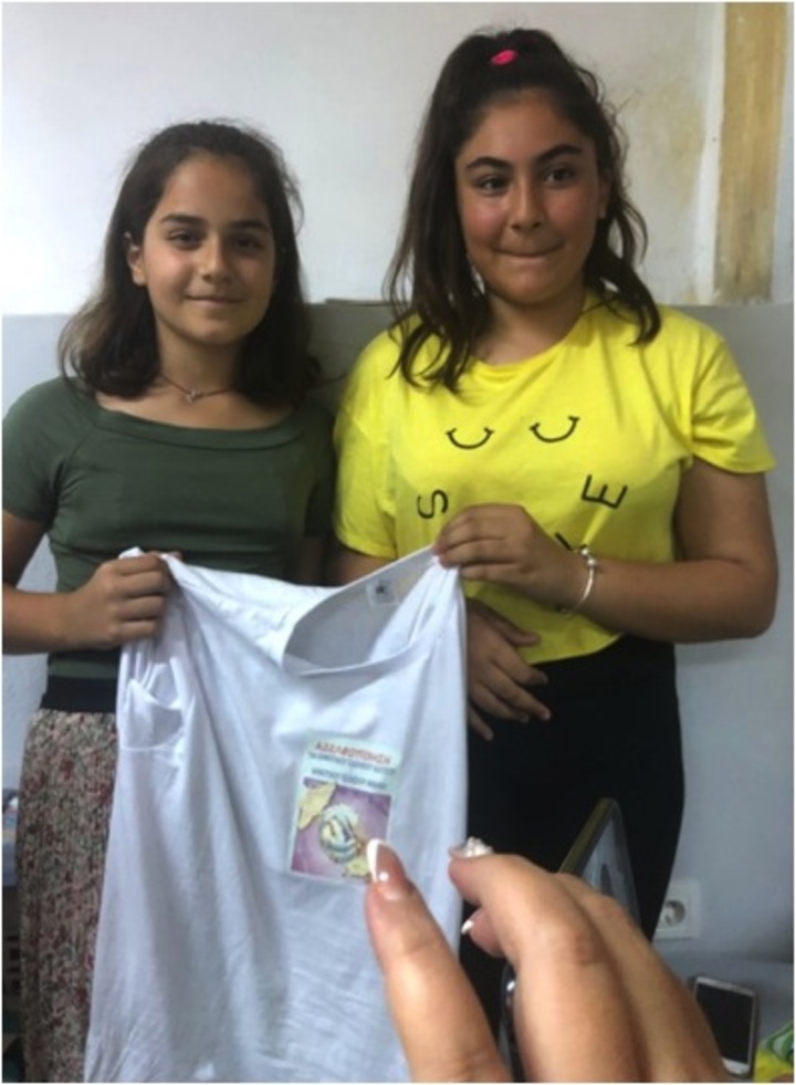 Μαθήτρια του 1ου Δ.Σ. Ιαλυσού δίνει το μπλουζάκι της αδελφοποίησης σε μαθήτρια του Δημοτικού Σχολείου Ίμβρου