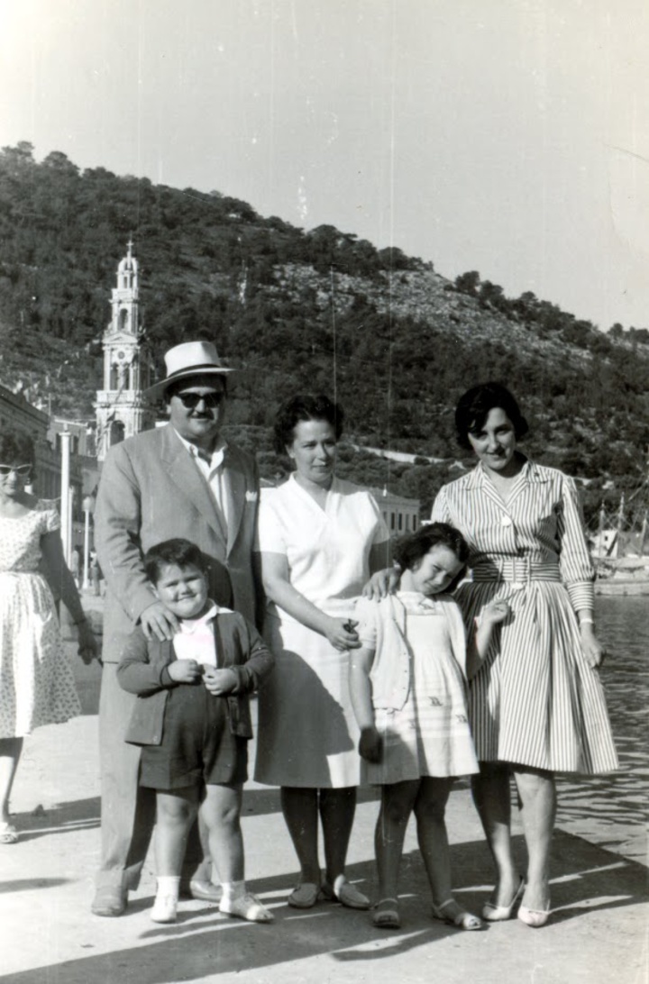 Οικογενειακή φωτογραφία στον Πανορμίτη, στη Σύμη. Στο βάθος φαίνεται το χαρακτηριστικό καμπαναριό. Από αριστερά επάνω ο πατέρας μου, η μητέρα μου, μια κυρία που δεν θυμάμαι ποια είναι και κάτω η αφεντιά μου και η αδελφή μου