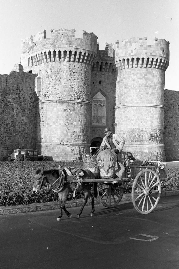 Ένας άνδρας περνά μπροστά από τα τείχη  της Παλιάς Πόλης, πάνω στην άμαξα με το άλογο