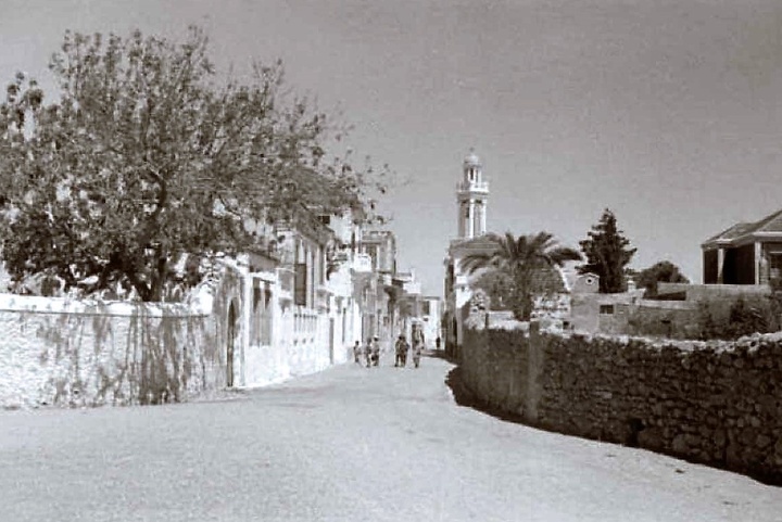 Στη φωτό η πρώτη πόρτα με το δέντρο ήταν το σπίτι της μάμμης Άννας, μιάς καλοκάγαθης κυριούλας που κάθε απόγευμα ποσπέριζε στην πόρτα της… Τότε όλοι ήταν, μπορεί να πει κανείς, μια οικογένεια…  (Φωτό Νίκου Κολλίγρη)