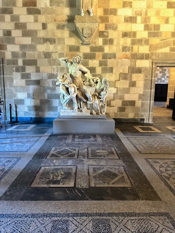 ΙΦΙΓΕΝΕΙΑ ΠΛΕΥΡΑΚΗ Από αίθουσες του παλατιού του Μεγάλου Μαγίστρου όπου υπάρχουν κίονες και κιονόκρανα, έπιπλα μεσαιωνικά, καθρέπτες, πίνακες, κηροστάτες και άλλα αντικείμενα συμπληρώνοντας τον διάκοσμο του επιβλητικού οικοδομήματος.