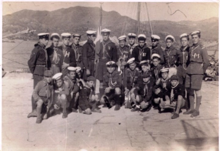 Η ομάδα των Ναυτοπροσκόπων στο λιμάνι στην παρέλαση της 25ης Μαρτίου 1952. Στην 2η σειρά από αριστερά: Θεοδόσης Μανωλάκης, Παντελής Αυλωνίτης, Μιχαήλος Χατζηγεωργίου, Άγνωστος, Νίκος Ιωαννίδης, Γιώργος Ορφανός, Ηρακλής Παπαδόπουλος, Μανώλης Κασσώτης, Κώστας Βασιλαράκης, Άγνωστος, Χαράλαμπος Κ. Ευσταθίου, Βάσος Μιχαηλίδης και Βάσος Καβουκλής. Στο μέσο της 1ης σειράς ο αρχηγός Βάσος Χατζημιχάλης μεταξύ των (από αριστερά) Γιάννη Κασσώτη, Ηλία Λαθουράκη, Μανώλη Καρακατσάνη, Χαρή Ορφανού, Ανδρέα Μακρή, Ηλία Ματσάκη, Αγνώστος, Ντίνου Καραξή, Γιώργου Μακρή, Νίκου Χατζημιχάλη και Χαρή Ζαβόλα