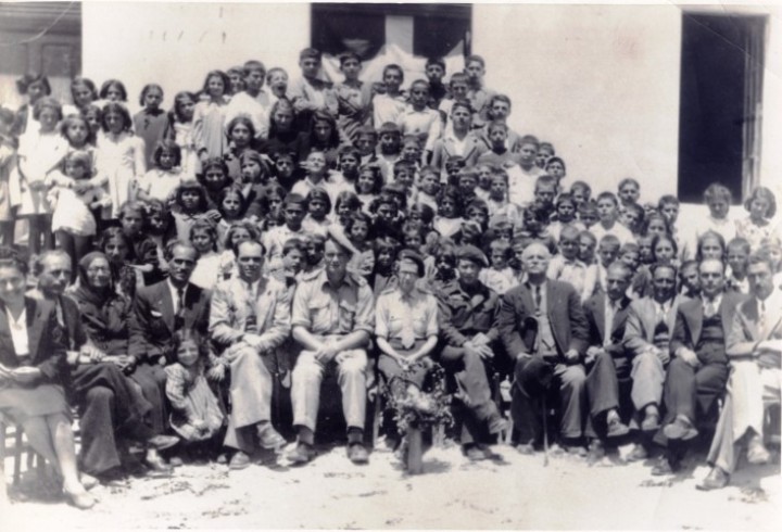 Άγγλοι και Καρπάθιοι αξιωματούχοι με τους δασκάλους των Πηγαδίων. Από αριστερά Φωτεινή Πιττά, Λάζαρος Κοσμάς, Μαρία Μακρή, Γιάννης Οικονομίδης, Ιορδάνης Καραξής, δύο αξιωματικοί με μια Αγγλίδα, Ιωάννης Φιλιππίδης (δήμαρχος), Άγνωστος, Μανώλης Λάμπρος, Κωνσταντίνος Λειβαδιώτης, Βάσσος Οικονομίδης. British and Karpathian officials with the of Pigadia scool. From left Fotini Pitta, Lazaros Kosmas, Maria Makri, John Economidis, Jordan Karaxis, two officers with a British lady, John Filippidis (mayor), Unknown, Manolis Lambros, Konstantine Livadiotis, Vassos Economidis.