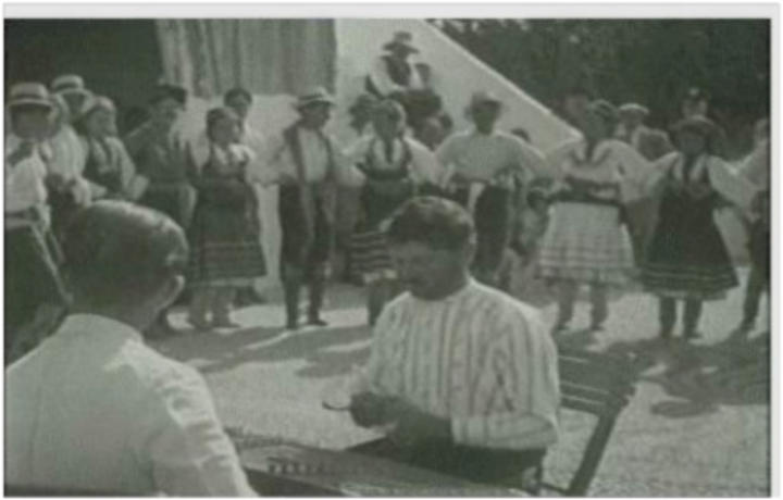 1922: Κάτοικοι της Κρητηνίας με το σαντούρι και το βιολί χορεύουν στην αυλή της εκκλησίας του χωριού τους.